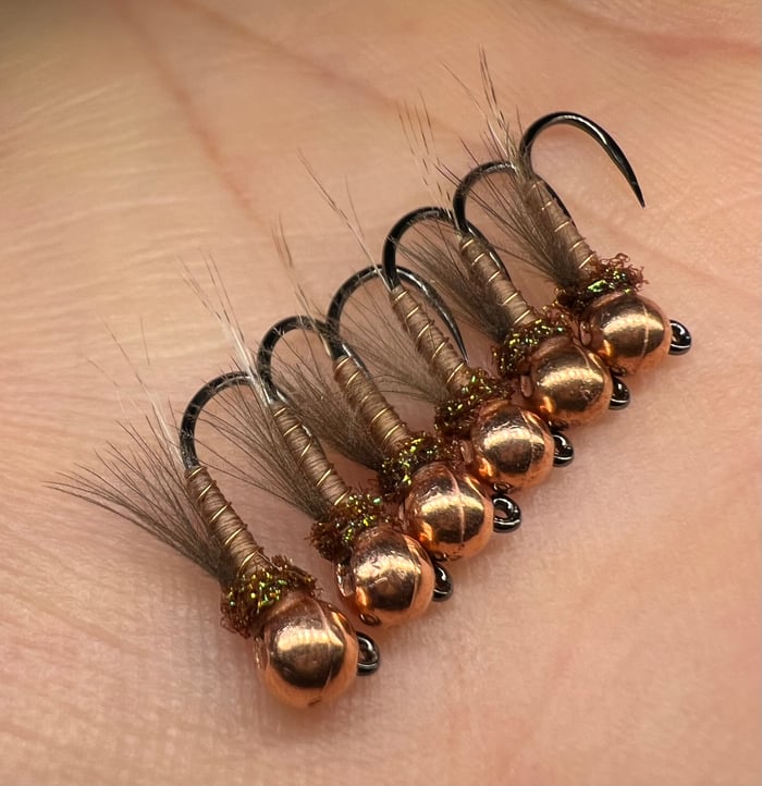 Fleeger's Rust Runner — the slim, copper-headed, natural-toned nymph, a Fleeger's original, sitting jig-style on a palm
