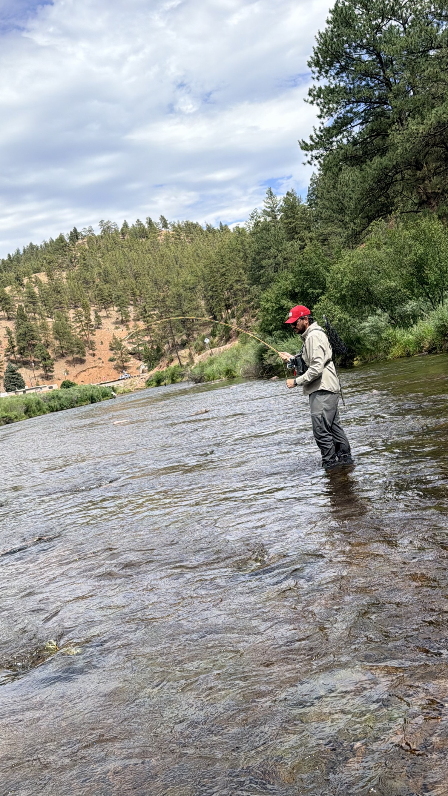 A fly rod bent deep into a running fish on a clear South Platte canyon run — the load under a real fish is where a blank shows you what it's actually made of.